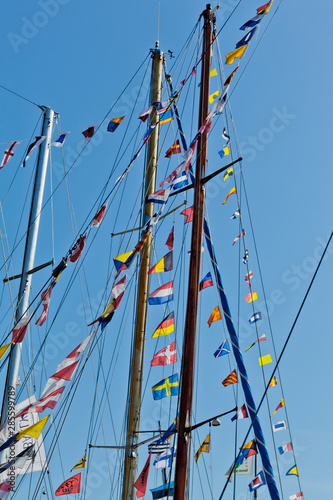 different international nautical flags on the mast of a sailing boat mast are fluttering in the wind