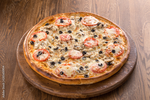 Italian Pizza with olives, sliced mushrooms, tomato sauce and cheddar isolated on wooden background