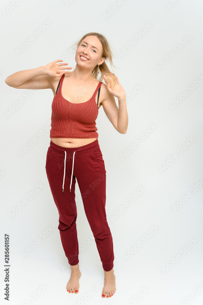 Full length studio portrait of a pretty young happy blonde woman in a tracksuit on a white background. He smiles, talks, shows with his hands, moves, shows emotions. Full length studio portrait of a pretty young happy blonde woman in a tracksuit on a white background. He smiles, talks, shows with his hands, moves, shows emotions.