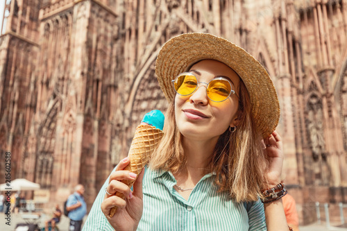 Happy asian girl tourist eating delicious ice-cream gelato in front of the hige Cathedral in Europe. Fun and joyful travel concept photo