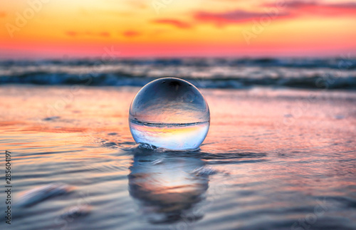 Beautiful sunset on the beach in Slowinski National Park near Leba, Poland. View through a glass, crystal ball (lensball) for refraction photography. Wild, untouched nature.