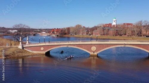 Aerial over the John W. Weeks Footbridge reveals Harvard University campus on the Charles River with rowing crew.