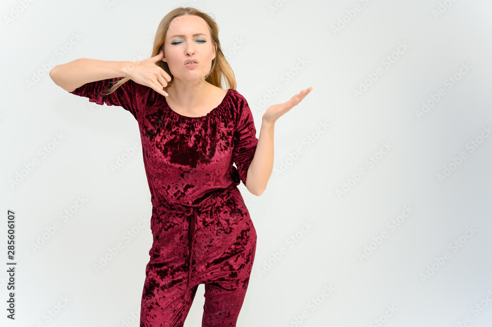 Studio knee-length portrait of a pretty beautiful young happy blonde woman on a white background in red overalls. Smiling, talking, showing emotions. Studio knee-length portrait of a pretty beautiful young happy blonde woman on a white background in red overalls. Smiling, talking, showing emotions.