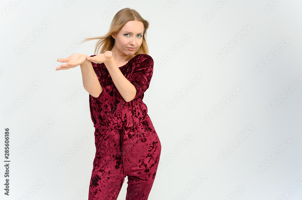 Studio knee-length portrait of a pretty beautiful young happy blonde woman on a white background in red overalls. Smiling, talking, showing emotions. Studio knee-length portrait of a pretty beautiful young happy blonde woman on a white background in red overalls. Smiling, talking, showing emotions.