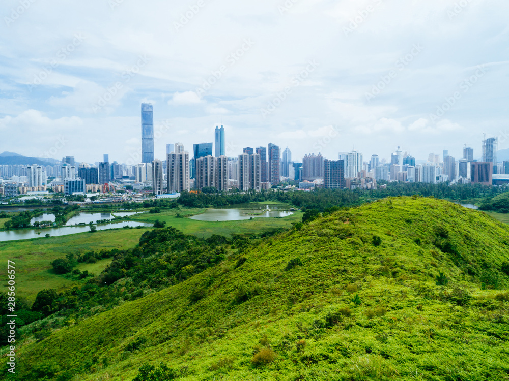 Aerial view of rural green fields with fish ponds on Hong Kong and the skylines of Shenzhen