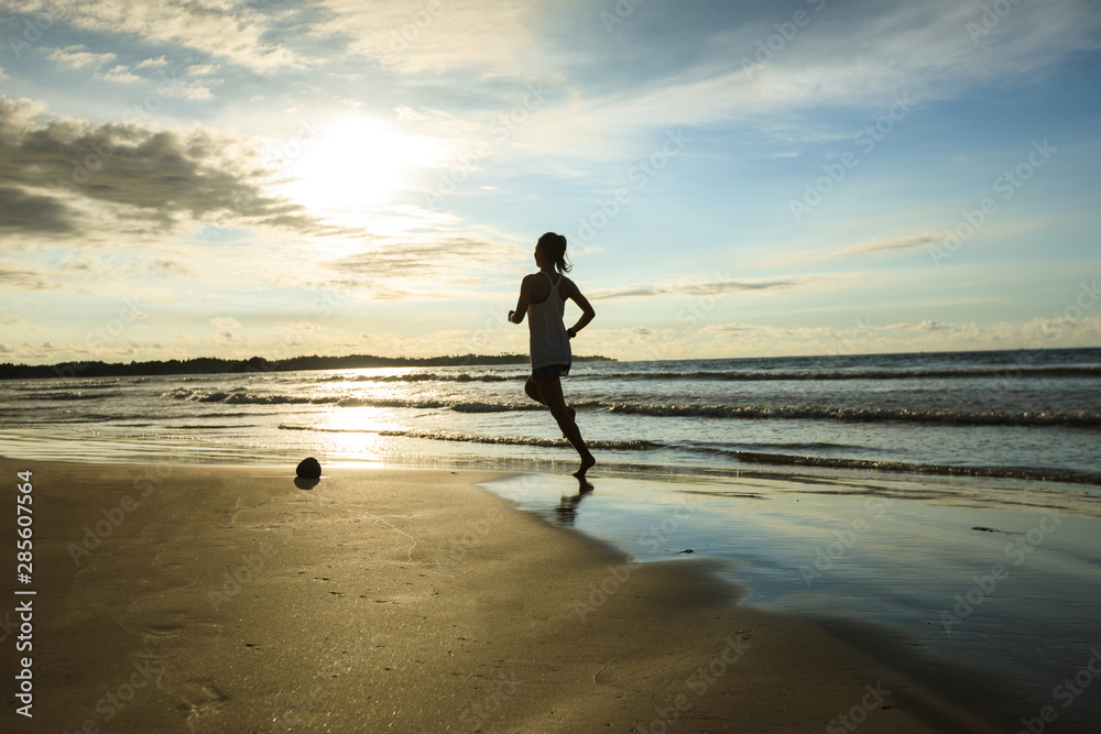 Fitness woman runner running on sunrise beach