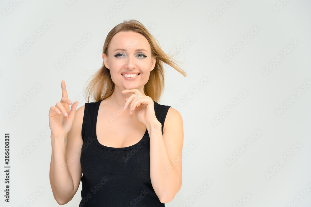 Studio waist-length photo portrait of a pretty beautiful young happy blonde woman on a white background in a black t-shirt. Smiling, talking, showing emotions.