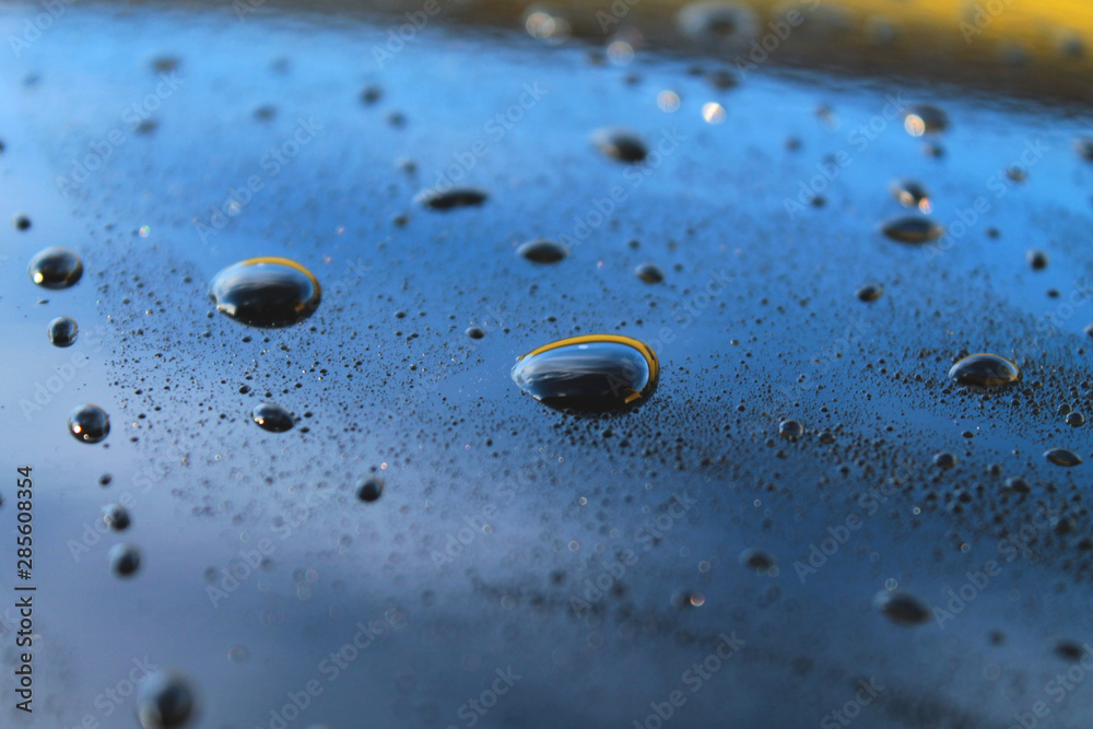 Big water droplets closeup on polished car paint body. Waxed car body