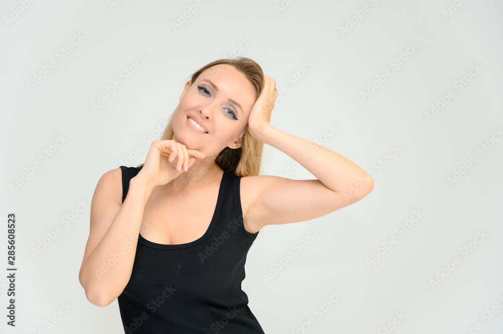 Studio waist-length photo portrait of a pretty beautiful young happy blonde woman on a white background in a black t-shirt. Smiling, talking, showing emotions. Studio waist-length photo portrait of a pretty beautiful young happy blonde woman on a white background in a black t-shirt. Smiling, talking, showing emotions.