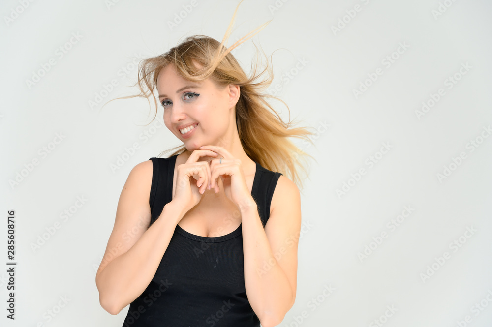 Studio waist-length photo portrait of a pretty beautiful young happy blonde woman on a white background in a black t-shirt. Smiling, talking, showing emotions. Studio waist-length photo portrait of a pretty beautiful young happy blonde woman on a white background in a black t-shirt. Smiling, talking, showing emotions.