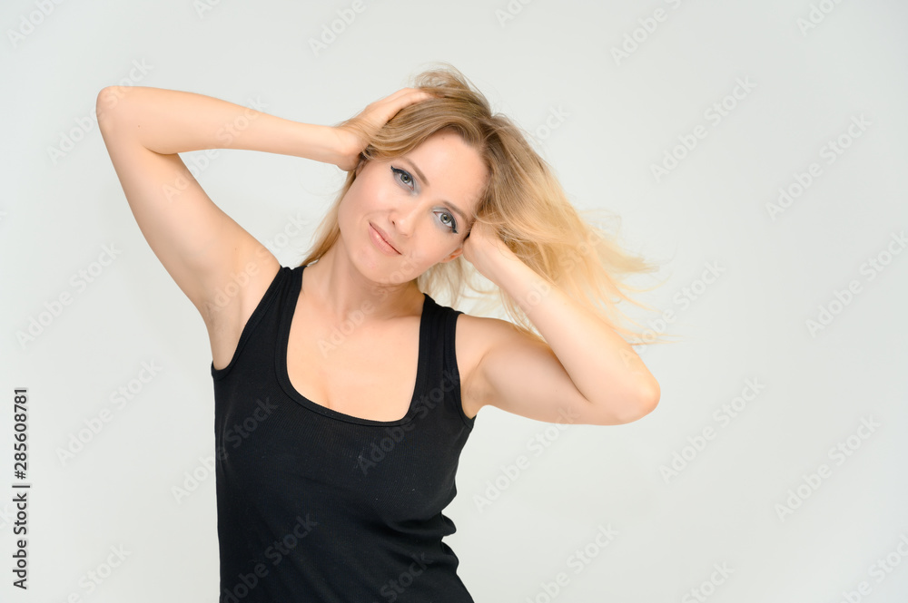 Studio waist-length photo portrait of a pretty beautiful young happy blonde woman on a white background in a black t-shirt. Smiling, talking, showing emotions.