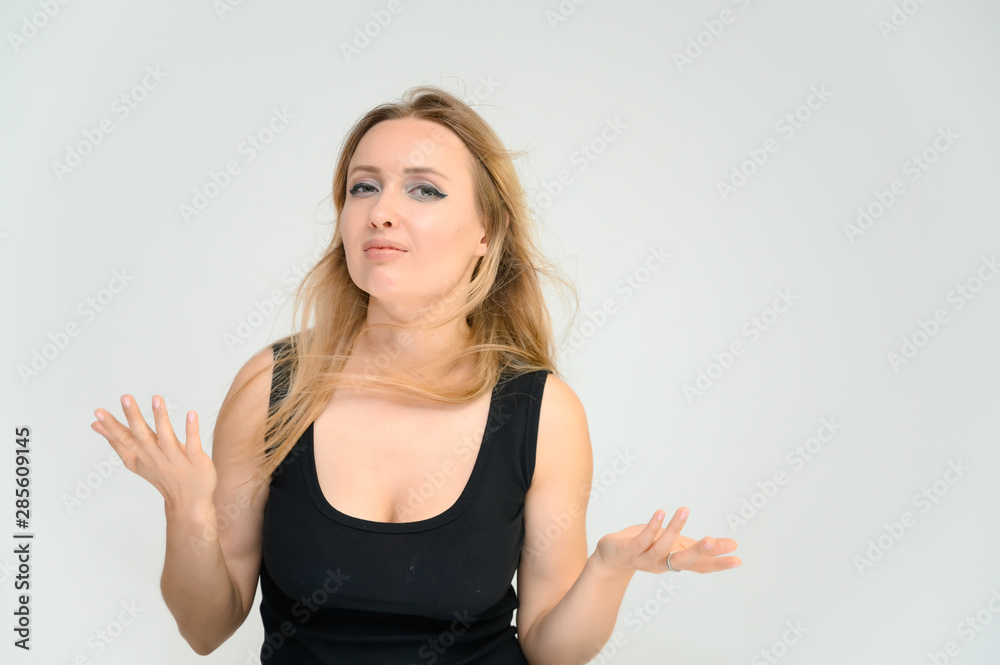 Studio waist-length photo portrait of a pretty beautiful young happy blonde woman on a white background in a black t-shirt. Smiling, talking, showing emotions. Studio waist-length photo portrait of a pretty beautiful young happy blonde woman on a white background in a black t-shirt. Smiling, talking, showing emotions.