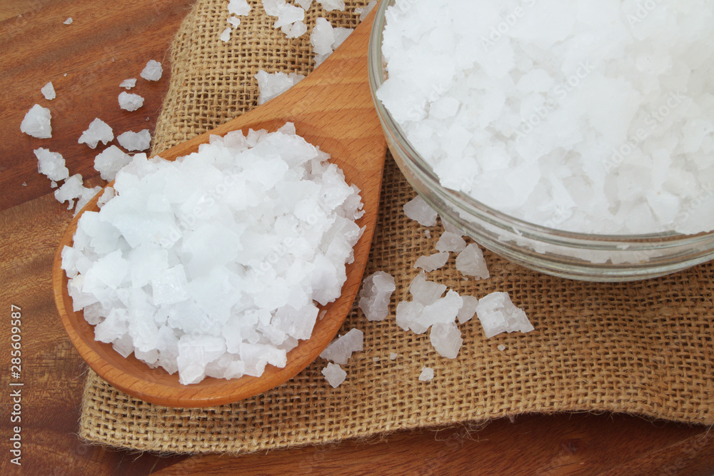 Coarse salt in wooden spoon and glass bowl on burlap sack close up Coarse salt in wooden spoon and glass bowl on burlap sack close up