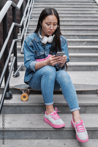 Korean skater girl with smart phone outdoors