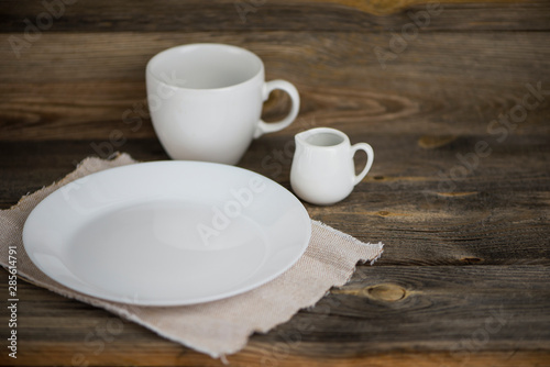empty white plate with cup and ceramic jug on old wooden background