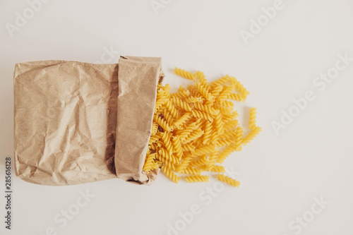 Spiral pasta in a paper bag on a white background. Top view. Copy, empty space for text