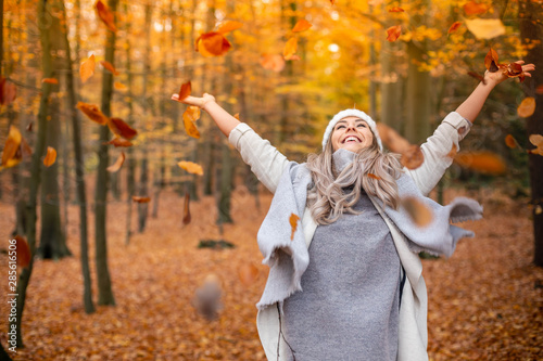 Girl walking in the park in autumn and smiles with open arms