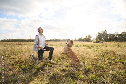 Side view of man training mongrel dog in grass on meadow. © Alexandr