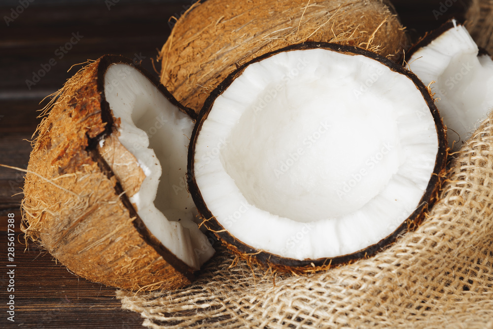 Broken coconut on a dark aged wooden table close up