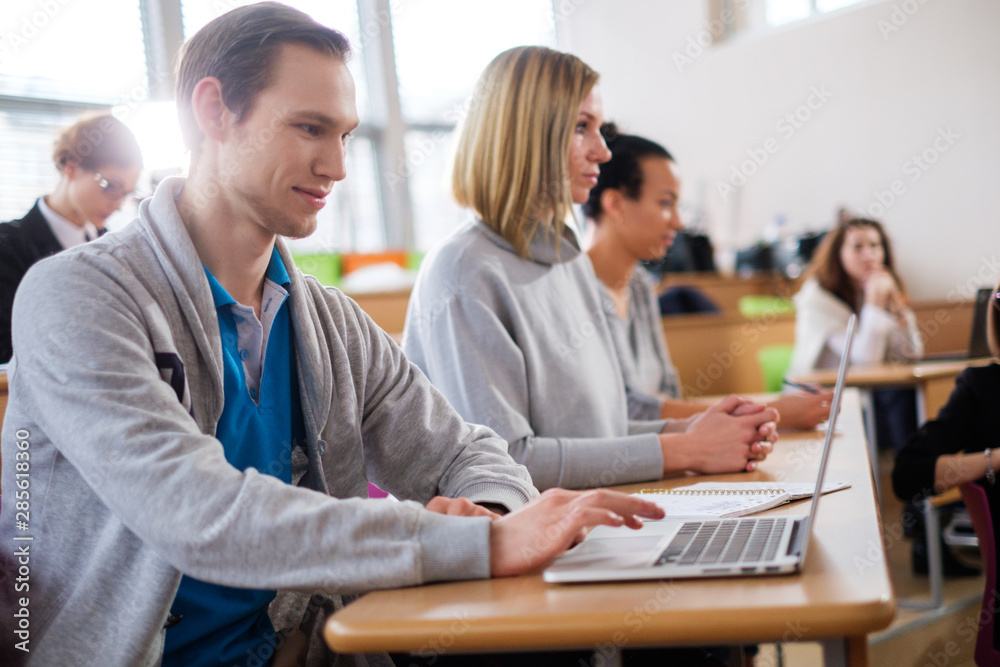 Man with laptop among students in an auditorium Man with laptop among students in an auditorium