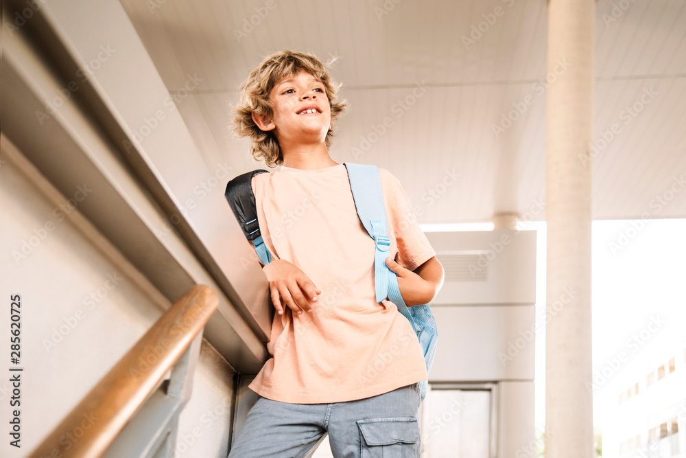 portrait of a happy Caucasian boy with a school bag, waiting for his classmates to enter school. first day of class. portrait of a happy Caucasian boy with a school bag, waiting for his classmates to enter school. first day of class.