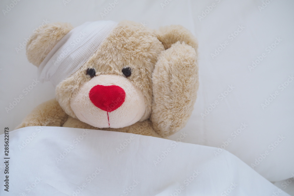 Teddy bear with a wound dress, wound and broken hands. Sleeping in bed. Sickness of children