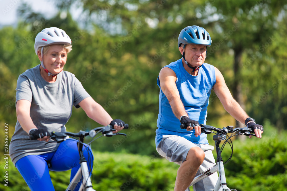 Naklejka premium Active senior couple riding bicycle in park