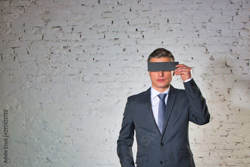 Obraz na plátně Mature businessman covering eyes with paper against white brick wall at office