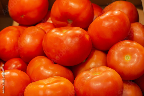 Red fresh tomatoes on a market counter, background wallpaper