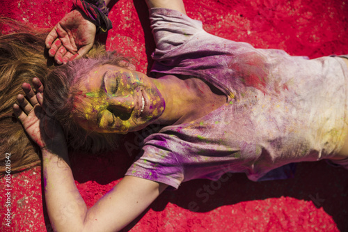 An overhead view of young women lying on red holi powder
