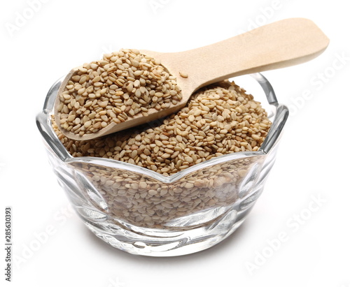 Organic integral sesame seeds with wooden spoon and glass bowl isolated on white background