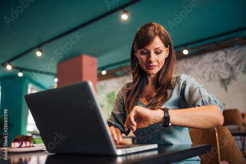 Foto Portrait of a woman checking time on wristwatch at the cafe.