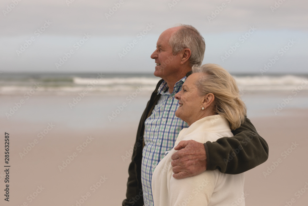 Senior couple standing with arm around at the beach 