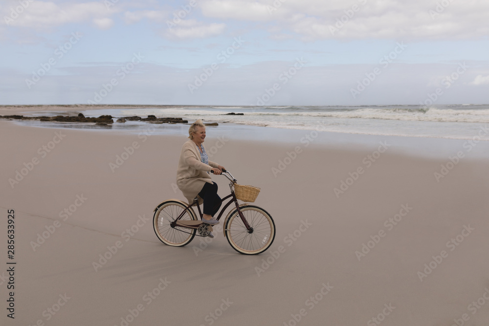 Fototapeta premium Happy senior woman riding bicycle at the beach 