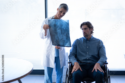 Mature female doctor showing x-ray report to patient in clinic photo