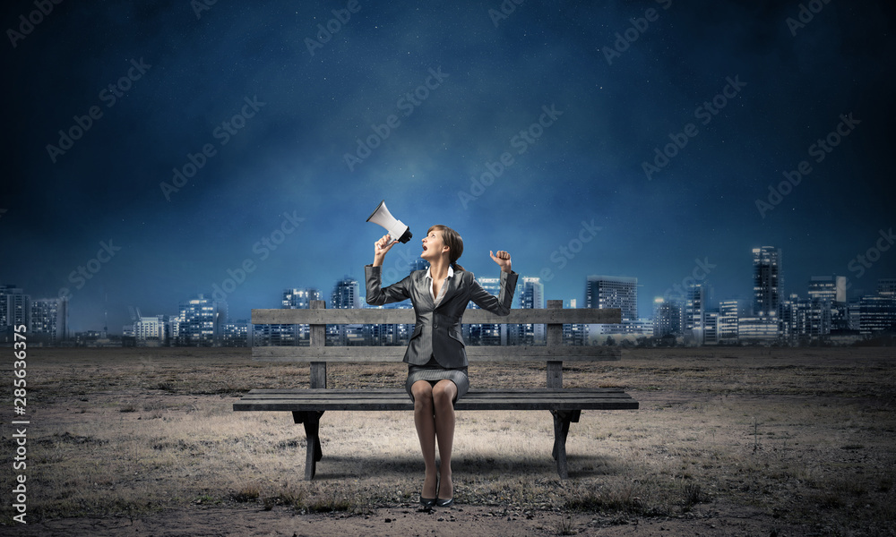 Business woman with megaphone on wooden bench Business woman with megaphone on wooden bench