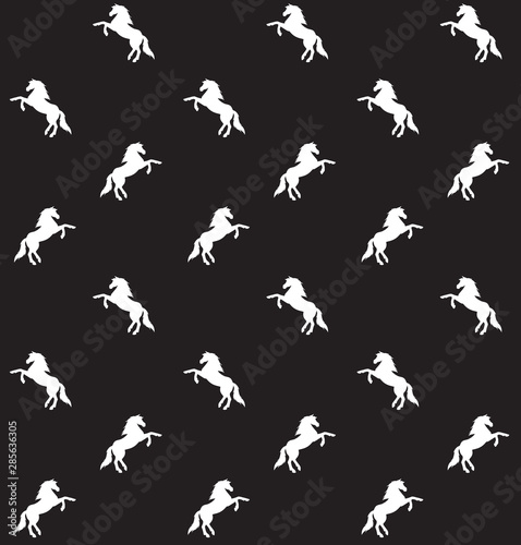 Vector seamless pattern of white unicorn silhouette isolated on black background © Sweta