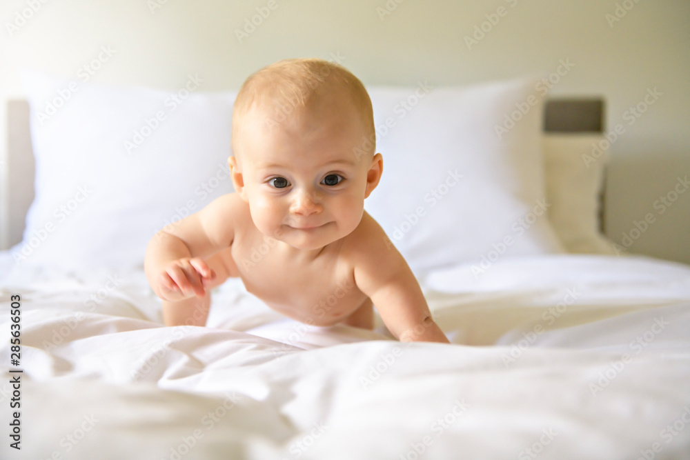 Cute happy baby girl in diaper on bed