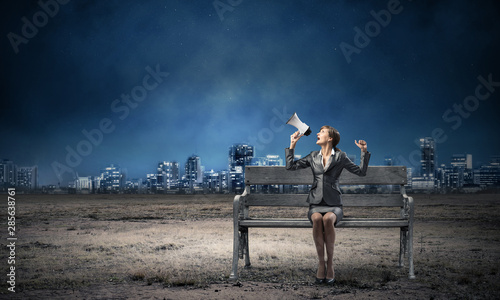 Business woman with megaphone on wooden bench