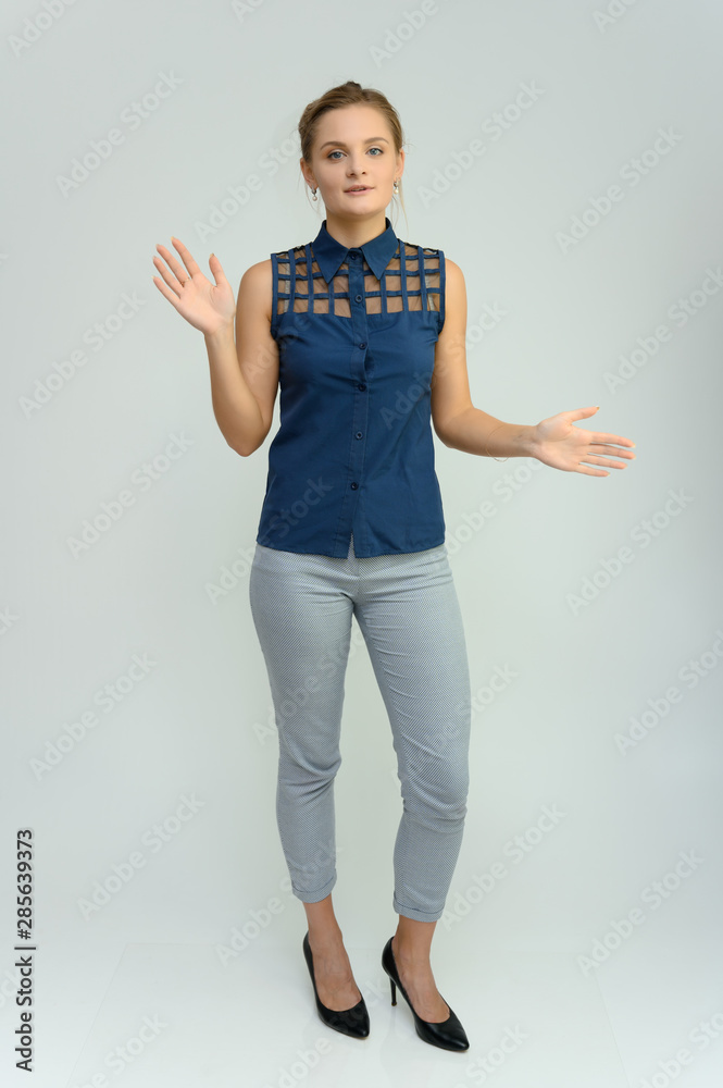 Full length studio portrait of a pretty young woman girl in a business suit on a white background. He stands right in front of the camera, explains, shows his hands with emotions. Full length studio portrait of a pretty young woman girl in a business suit on a white background. He stands right in front of the camera, explains, shows his hands with emotions.