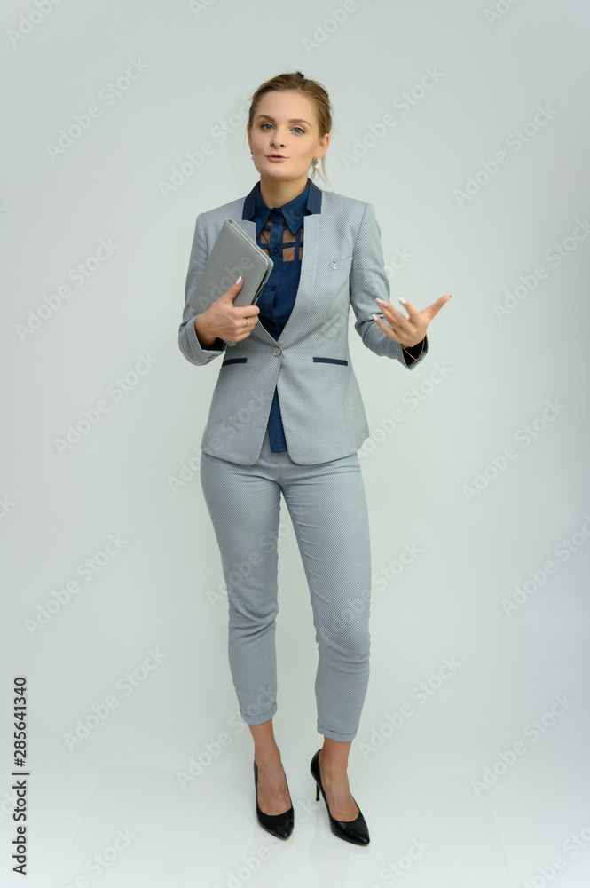 Full length studio portrait of a pretty young woman girl in a business suit on a white background with a folder in hands. He stands right in front of the camera, explains, with emotion. Full length studio portrait of a pretty young woman girl in a business suit on a white background with a folder in hands. He stands right in front of the camera, explains, with emotion.