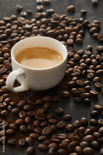 White cup with espresso on dark surface with coffee beans © LIGHTFIELD STUDIOS