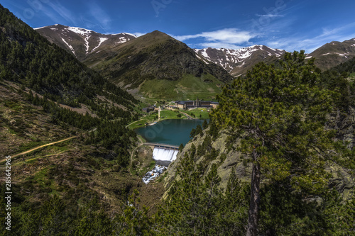Beautiful pyrenees landscape with a dam, a building & some snow