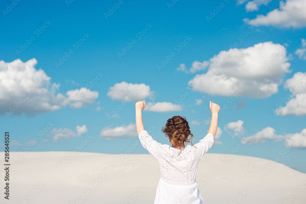Confident young woman raising her fist up in the sky. Feeling motivated. Confident young woman raising her fist up in the sky. Feeling motivated.
