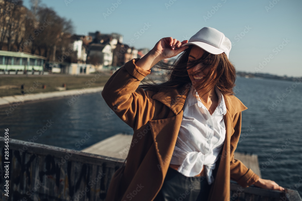 Beautiful Young Stylish Girl in Coat Walking in the Spring Beach at Sunset