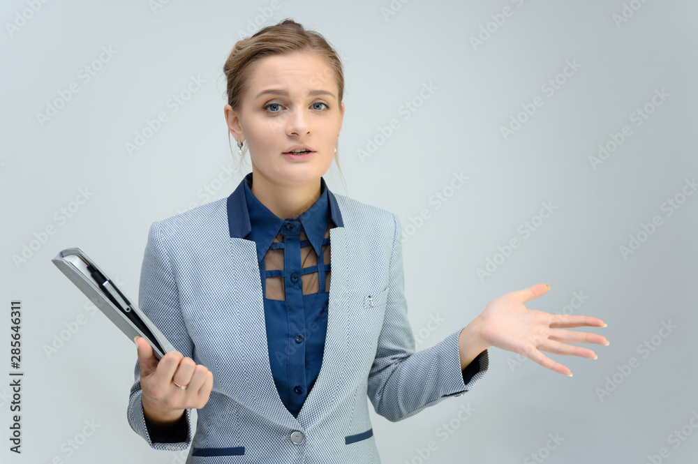 Studio photo a waist-high portrait of a cute young woman girl in a business suit on a white background with a folder in hands. He stands right in front of the camera, explains, with emotion. Studio photo a waist-high portrait of a cute young woman girl in a business suit on a white background with a folder in hands. He stands right in front of the camera, explains, with emotion.