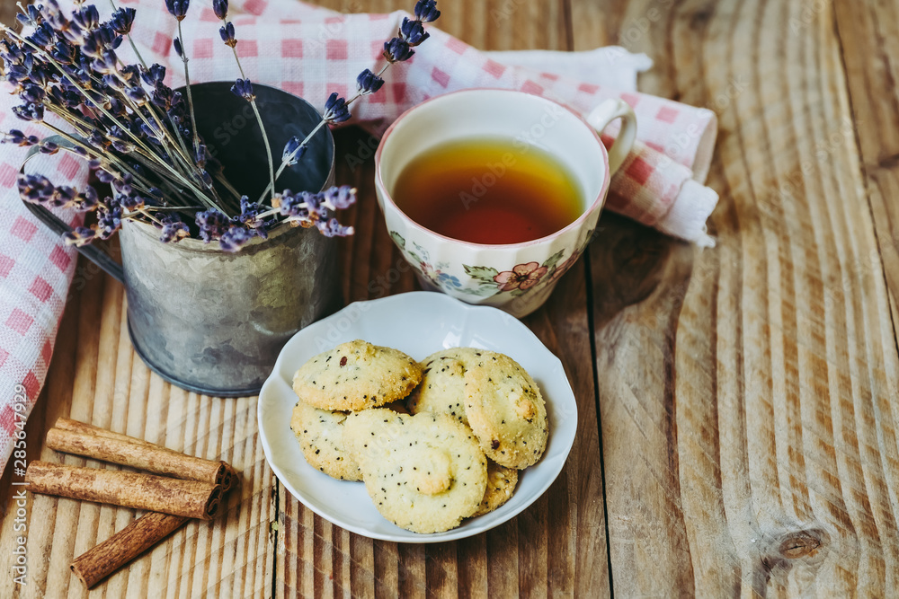Gouter avec thé citron et biscuits sans gluten à la cannelle, fond bois vintage et pot en métal avec de la lavande Gouter avec thé citron et biscuits sans gluten à la cannelle, fond bois vintage et pot en métal avec de la lavande
