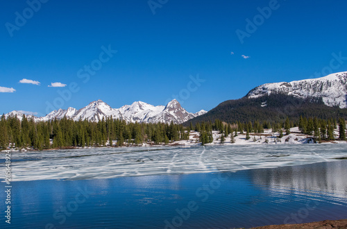 Fototapeta Naklejka Na Ścianę i Meble -  Molas Lake with melting ice, trees and snow-dappled mountains in Colorado