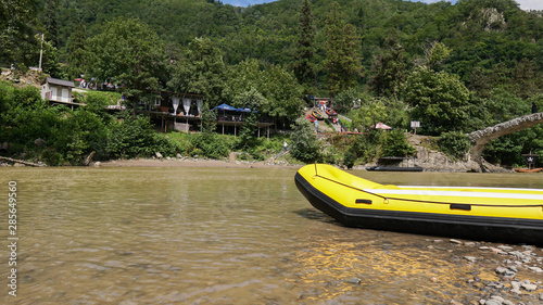 Yellow inflatable boat on the river or lake near the shore in a clear summer day. Tourist recreation and fishing. Have a fun weekend with a friend. Relaxation, sports, holidays.