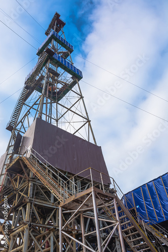 Drilling rig with a tower tower. Downstairs is the drilling equipment. A deep well is being drilled in the northern field for oil and gas production. Summer day. Blue cloudy sky.